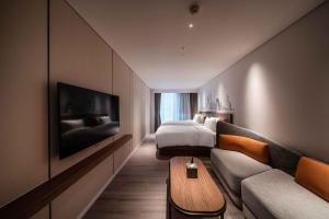 上海上海陆家嘴世博中心逸扉酒店的酒店客房配有床、沙发和电视。