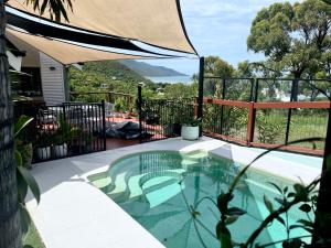 Hideaway BayThe Cowrie Shell, Hydeaway Bay的庭院内一个带遮阳伞的游泳池