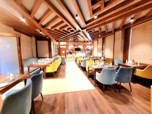斯利那加Hotel Meerz , Srinagar的餐厅设有木制天花板和桌椅