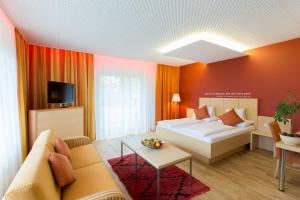 格拉茨Hotel Süd Graz的客房设有床、沙发和电视。
