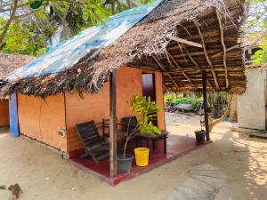 阿鲁甘湾Rainbow Village Cabanas的一个带草屋顶和椅子的小小屋