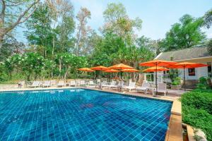 北碧Comsaed River Kwai Resort SHA的一个带椅子和遮阳伞的游泳池