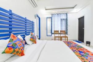 斋浦尔FabHotel Istana Inn的卧室配有一张带彩色枕头的大型白色床。