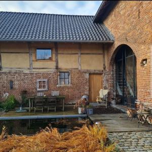 EckelradeVakantiewoning in monumentale boerderij met yurt的砖屋,设有木甲板和桌子