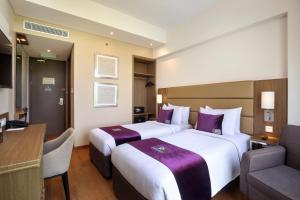 诗都阿佐Premier Place Surabaya Airport的酒店客房配有两张床和一张书桌