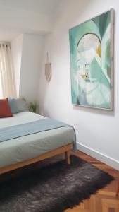 伦敦Charming bedroom in artist studio的卧室配有一张床,墙上挂有绘画作品
