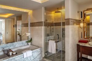 胡志明市Mia Saigon – Luxury Boutique Hotel的带浴缸和玻璃淋浴间的浴室。