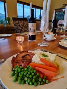Rev EstatesSilver Hill Lodge的桌上的一块肉和蔬菜,一瓶葡萄酒