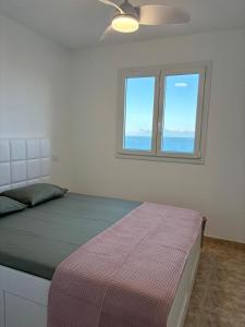 Playa del BurreroCasa Mirtilla的一间卧室配有一张带吊扇的床和2扇窗户。