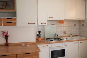 比比翁Cozy charm near the beach - Beahost的厨房配有白色橱柜和炉灶烤箱。