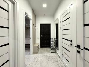 敖德萨Arcadia Luxury Apartments的一条带白色墙壁和黑色门的走廊
