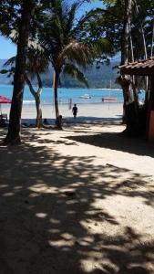 乌巴图巴Calumar Guest House的棕榈树海滩上散步的人