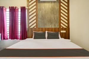 科钦GYPSY HOTEL CUSAT的一间卧室配有一张大床和紫色窗帘