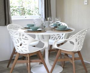 洪德洛Welkom in het beachbos I Onthaasten op de Veluwe的白色的餐桌,配有两把椅子和白色的桌子及玻璃杯