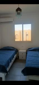 沙姆沙伊赫sea street hadaba的一间卧室配有两张床、一个吊灯和两个窗户。
