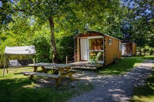 Foncine-le-HautAuberge de la Rivière的木制拖车,带野餐桌和帐篷