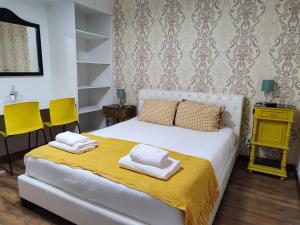 蓬塔德尔加达古老广场亚速尔旅馆的一间卧室配有白色床和两张黄色椅子