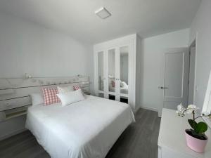 宏达海滩White Serenity的白色卧室配有大白色床和粉红色枕头