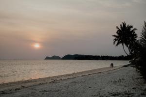 帕干岛Soukaina Beach Bungalow的棕榈树在海滩上行走的人