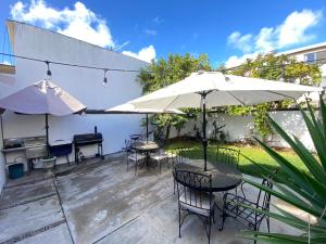 提华纳Quetzal House的一个带桌椅和遮阳伞的庭院