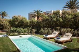 赫索尼索斯贝拉海滩酒店的一个带2把躺椅的游泳池和一个游泳池