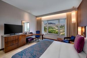 马斯喀特马斯喀特OCEC皇冠假日酒店的酒店客房配有一张床、一张书桌和一台电视。