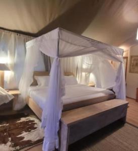 SekenaniDan Maasai Mara safari camp的一间卧室配有一张带天蓬的白色床