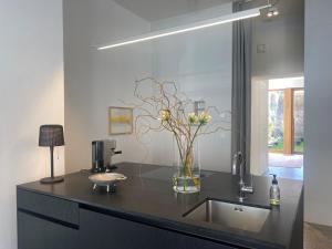 科隆Zehuus Gartenstudio mit Terrasse的黑色柜台,花瓶里放着鲜花
