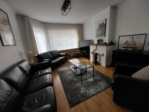 德帕内Repos St Elisabeth nabij Plopsaland的客厅配有黑色真皮沙发和桌子