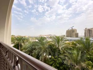 迪拜Dar Vacation - Bright and Charming 1 BR Apartment, Madinat Jumeirah Living的阳台享有棕榈树和建筑的景致。