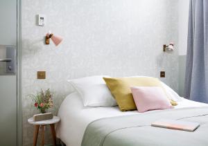 巴黎亨丽埃特酒店的卧室配有白色床和粉色及黄色枕头