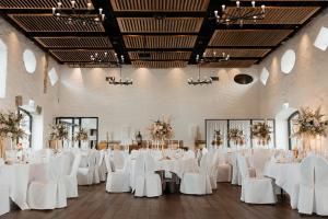 IslikonHotel Greuterhof的一个带白色桌子和白色椅子的婚礼大厅