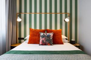 里昂Hôtel Edmond W Lyon Part-Dieu的一张带橙色枕头和绿色及白色条纹的床