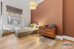 伦敦Parea Living - South Kensington, Elegant 1-Bedroom Flat, WFH Desk的一间卧室配有一张床、一个梳妆台和一扇窗户。