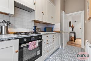 伦敦Parea Living - South Kensington, Elegant 1-Bedroom Flat, WFH Desk的厨房配有白色橱柜和炉灶烤箱。