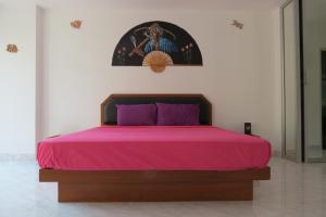 南芭堤雅仲天塔莱1号景观公寓的一张带粉红色床罩的床和墙上的照片