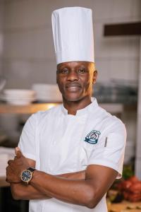 戈马Cap Kivu Hôtel的站在厨房里的厨师,手臂交叉