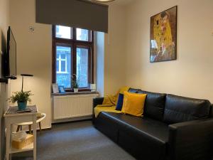 克拉科夫Millenium Apartments的客厅配有黑色真皮沙发和黄色枕头。