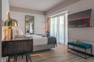 里斯本Pestana Lisboa Vintage City Center Suites的酒店客房设有一张床、一张书桌和一台电视机。