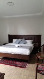 纳库鲁Twiga Whitehouse Villas的一间卧室配有一张大床和木制床头板