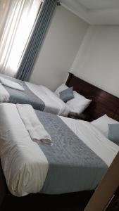 纳库鲁Twiga Whitehouse Villas的两张睡床彼此相邻,位于一个房间里
