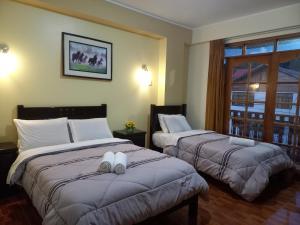 奥克萨潘帕Hospedaje "LOS QUETZALES DE OXAPAMPA"的酒店客房设有两张床和窗户。