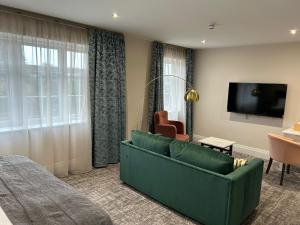 谢伯恩The Hillbrook Hotel & Spa - Sherborne的客厅配有绿色沙发和电视