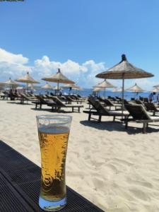 都拉斯COSMO Beach Hotel的坐在海滩上的桌子上喝一杯啤酒