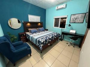巴里奥斯港Departamento Centrico, cerca de todos los balnearos de Puerto Barrios的一间卧室配有一张床、一把椅子和镜子
