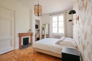 昂德雷济厄布泰翁Maison Martouret - Colodge的一间白色卧室,配有一张床和一个壁炉