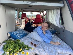 波尔蒂芒Rent a Blue Classics' s Campervan for your Road trip in Portimao -VOLKSWAGEN T3的躺在露营车床上的妇女