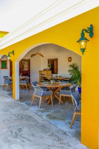 克拉伦代克Boutique Hotel Wanapa的庭院设有黄色的墙壁和木桌及椅子