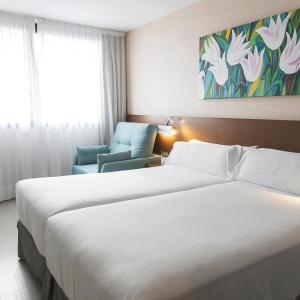 萨拉戈萨萨拉戈萨瑞市酒店及水疗中心的酒店客房,配有两张床和椅子
