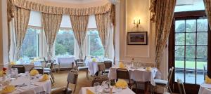 纽卡斯尔Enniskeen Country House Hotel的餐厅设有白色的桌椅和窗户。
